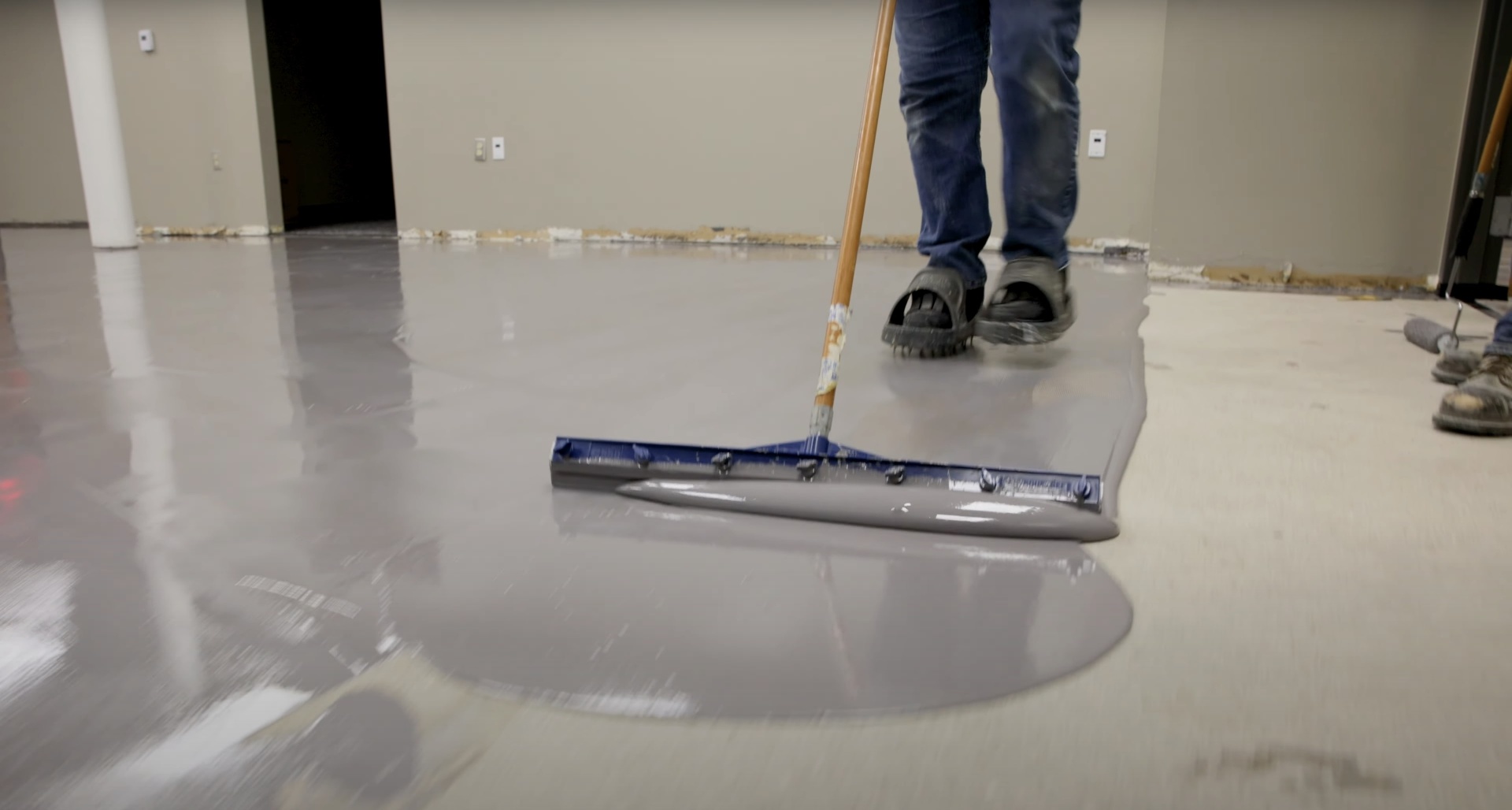 Expert concrete floor finishing by Hudson Concrete Construction Professional concrete floor finishing work with specialized squeegee tool